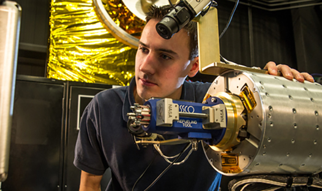 RROxiTT lead roboticist Alex Janas stands with the Oxidizer Nozzle Tool as he examines the worksite.